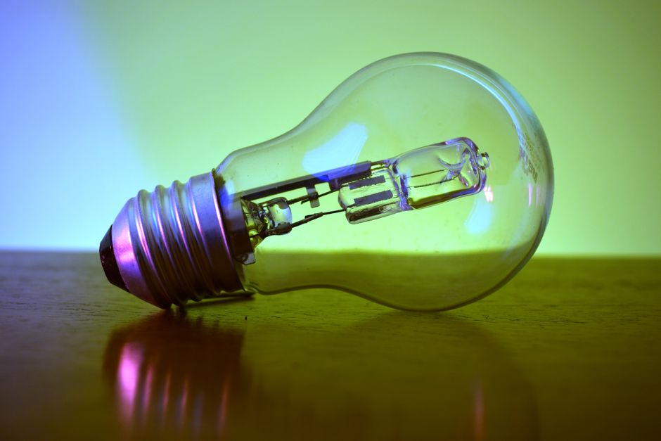 Colorful close-up of a light bulb reflecting vibrant hues on a surface, showcasing creative lighting.