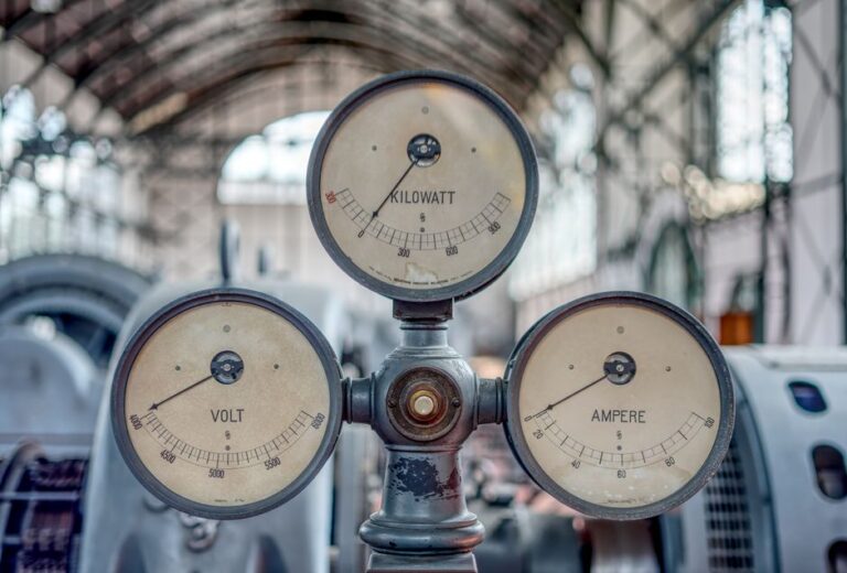 Close-up of vintage volt, ampere, and kilowatt gauges in an old industrial setting.