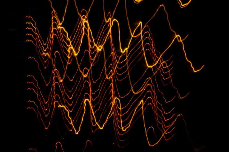 Long exposure of creative modern freezelight light painting with bright wavy lines creating patterns shining on black background in darkness