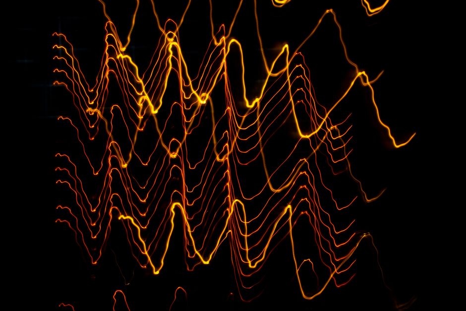 Long exposure of creative modern freezelight light painting with bright wavy lines creating patterns shining on black background in darkness